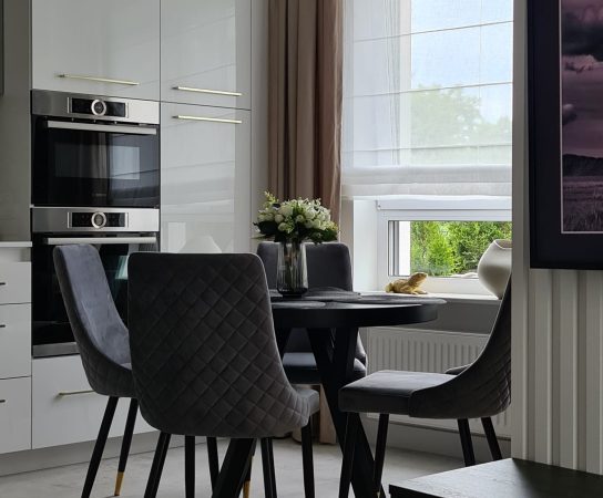 Kitchen / dining with high gloss white kitchen cabinets and black / grey round dining table and grey chairs