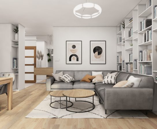 Elegant modern living room in a Warsaw apartment with dark blue upholstered sofa, abstract art, and classic wall trim.