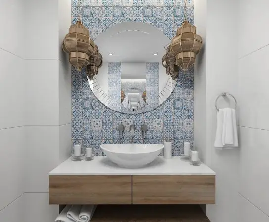Cloaks room with marroco style tiles, round mirror and floating cupboard / basin