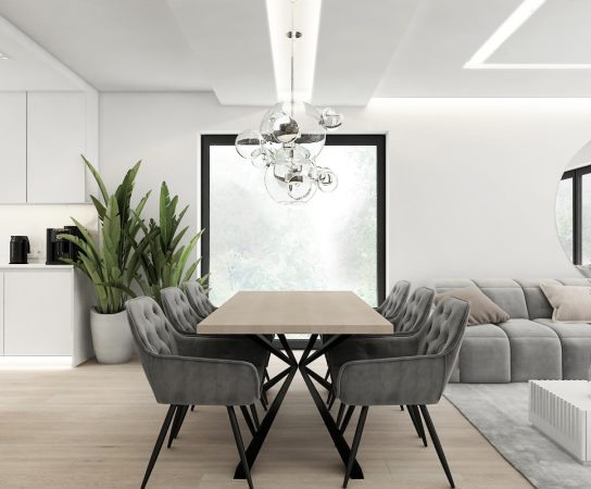 Minimalist open-plan dining area next to a contemporary kitchen island with grey velvet dining chairs and a unique chrome pendant light.